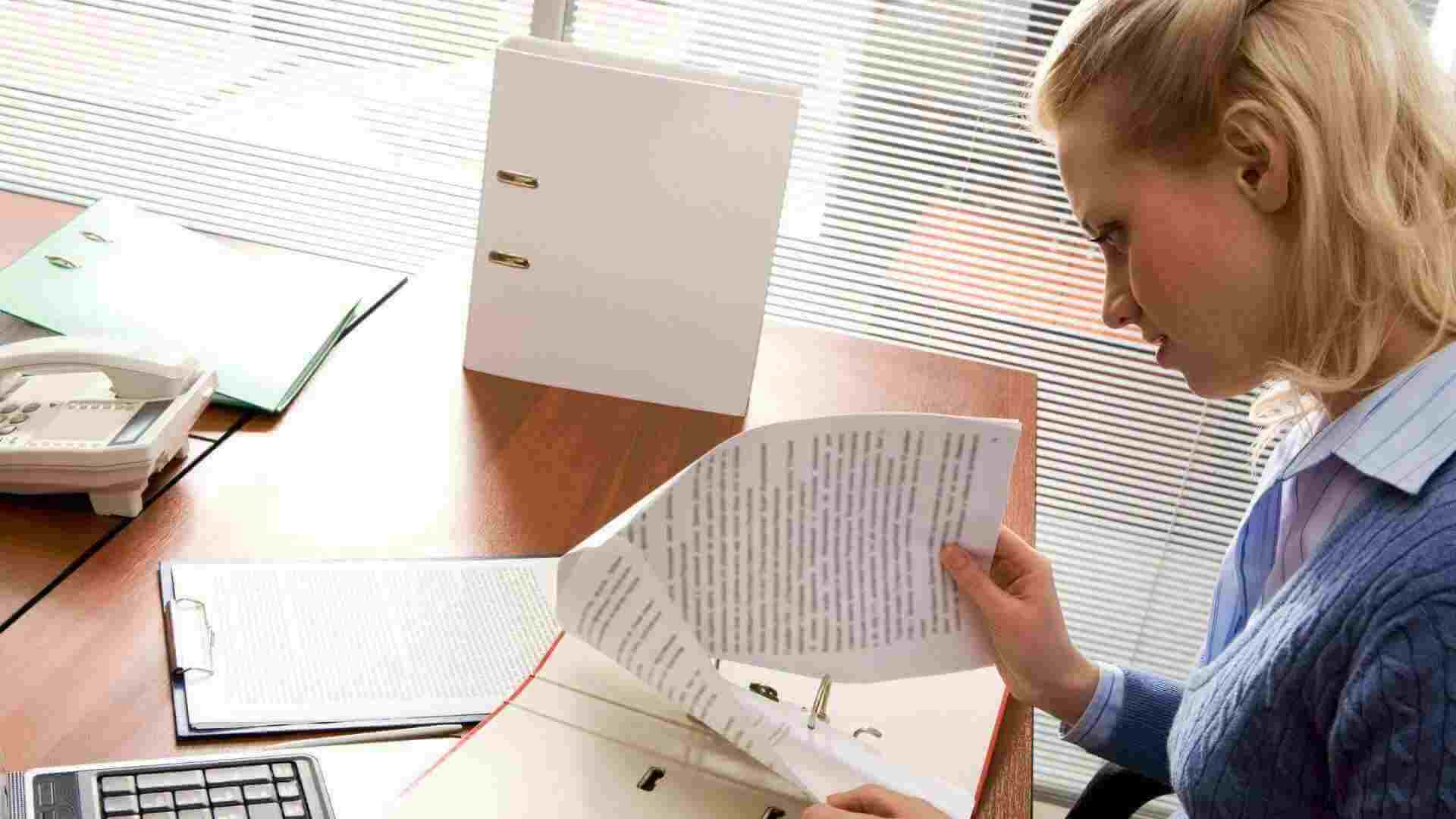 A blonde legal professional in a navy sweater and collared shirt going through the paperwork for an eviction notice in Texas.